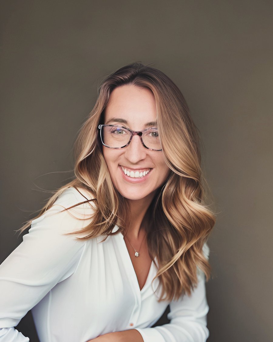 Jordan Fastenau, smiling, wearing glasses and a white blouse